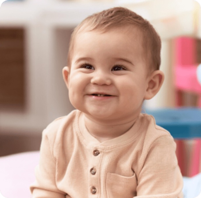 Child smiling in a vibrant classroom, embodying the joy of learning about Kids 1st.